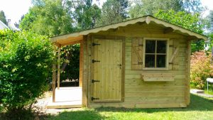 Abri de jardin en bois avec porche et fenêtre.