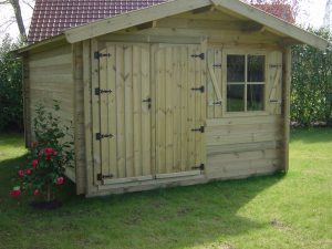 Abri de jardin en bois avec fleurs roses sur pelouse verte.