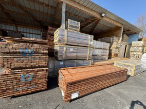 Stock de bois de construction sous abri, avec madriers et planches.