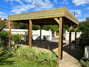 Abri de voiture en bois neuf, allée verdoyante.