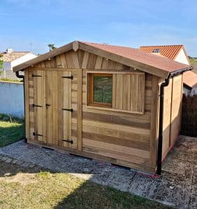 Abri de jardin en bois neuf, toiture cuivre, ciel bleu.