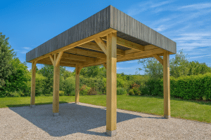 Carport moderne en bois et gris dans un jardin ensoleillé.