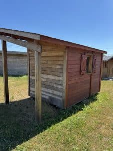Cabane en bois rouge et auvent sous ciel bleu.