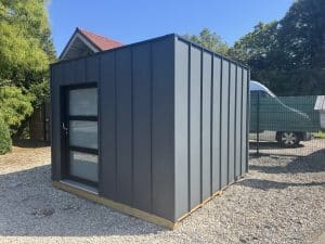 Abri de jardin moderne gris anthracite sur graviers ensoleillés