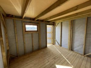 Intérieur de cabane en bois en construction avec plancher et isolation.